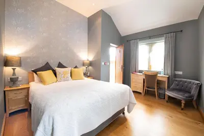a bedroom with a bed and a desk and a chair at The Red Lion Hinxton in Hinxton