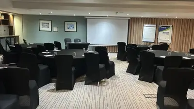 a conference room with tables and chairs and a screen at The Red Lion Hotel in Cambridge