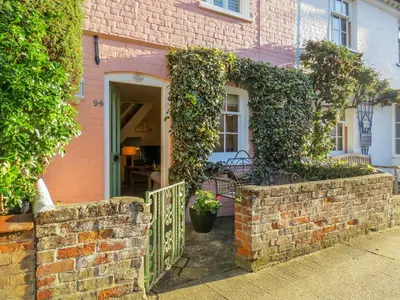 a pink brick house with a gate and ivy at Ivy Cottage in Aldeburgh