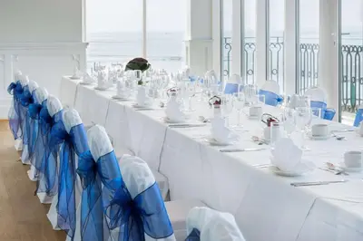 a long table with white tables and blue chairs at The Palace Hotel in Southend-on-Sea