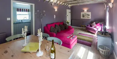 a living room with a pink couch and a table at Waterfront Cottage in Aldeburgh