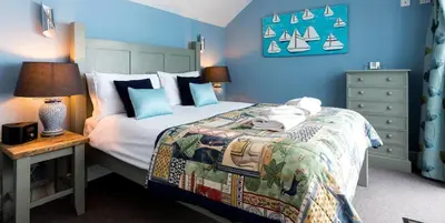 a bedroom with a bed and a table with a lamp at Waterfront Cottage in Aldeburgh
