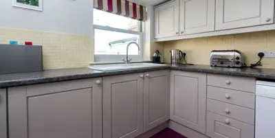 a kitchen with white cabinets and a sink and a window at Waterfront Cottage in Aldeburgh