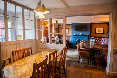 a dining room with a large wooden table and chairs at The Bushel by Greene King Inns in Bury Saint Edmunds