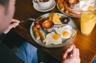 a person sitting at a table with a plate of breakfast food at The Bushel by Greene King Inns in Bury Saint Edmunds