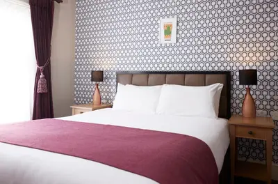a bedroom with a large bed with a purple blanket at The Bushel by Greene King Inns in Bury Saint Edmunds