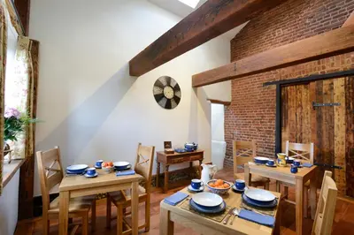 a dining room with wooden tables and chairs and a brick wall at Old Field Barn Luxury B&B in Attleborough