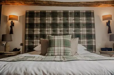 a bedroom with a bed with a plaid headboard at The White Hart Hotel in Hingham