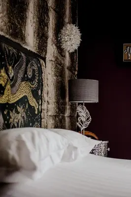 a bedroom with a bed with a lamp and a wall at The White Hart Hotel in Hingham