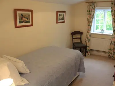 a bedroom with a bed and a chair and a window at Church Farmhouse B & B in Kennett