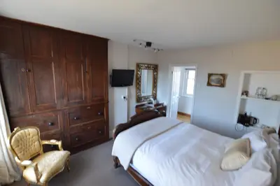 a bedroom with a large bed and a chair at Chantry Hotel in Bury Saint Edmunds