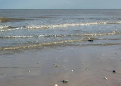 a beach with waves and rocks in the water at Esplanade Hotel - Clacton On Sea, Beachfront Hotel by OYO in Clacton-on-Sea