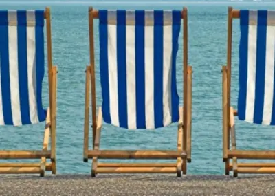 three beach chairs sitting on the beach near the water at Esplanade Hotel - Clacton On Sea, Beachfront Hotel by OYO in Clacton-on-Sea