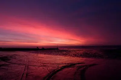 a sunset on a beach with tracks in the sand at Esplanade Hotel - Clacton On Sea, Beachfront Hotel by OYO in Clacton-on-Sea