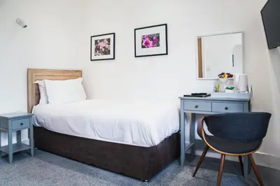 a bedroom with a bed and a desk and a chair at County Hotel in Chelmsford