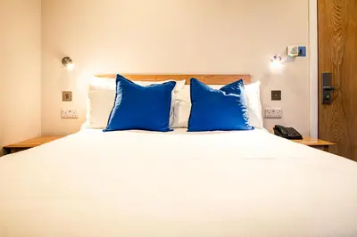 a large white bed with blue pillows on it at County Hotel in Chelmsford