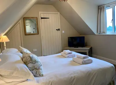 a bedroom with a white bed with towels on it at Fox Inn in Darsham