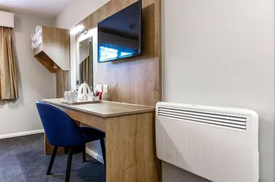 a room with a desk and a sink and a tv at Days Inn London Stansted Airport in Stansted Mountfitchet