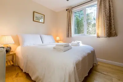 a bedroom with a large white bed with a window at The Retreat, Unique property located in calming woodland surroundings, Close to Aldeburgh and Thorpeness in Leiston