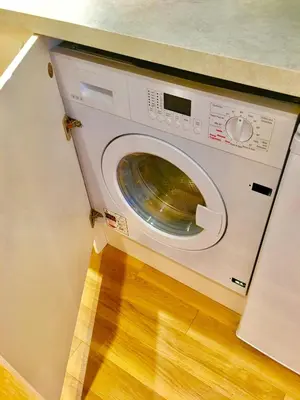 a washing machine in a kitchen with a wooden floor at Angel's (station accommodation) in Cambridge