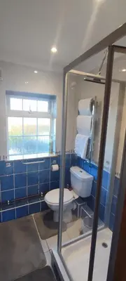 a blue bathroom with a toilet and a window at Shear Annexe Flat in Cambridge