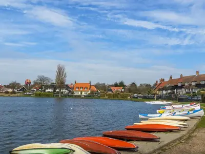 a row of boats are lined up on the water at 7 The Uplands in Thorpeness