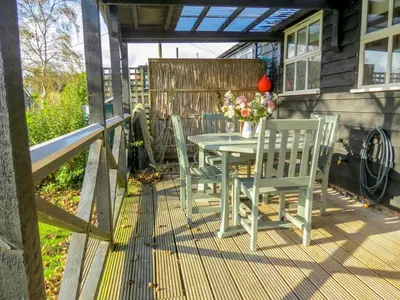 a patio with a table and chairs on a deck at 7 The Uplands in Thorpeness