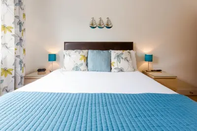 a bedroom with a large bed with a blue blanket at 1 Suffolk Cottage, Knodishall - Aldeburgh Coastal Cottages in Aldeburgh