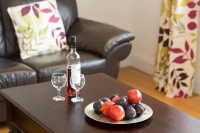 a plate of fruit and a bottle of wine on a table at 1 Suffolk Cottage, Knodishall - Aldeburgh Coastal Cottages in Aldeburgh
