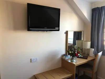 a room with a desk with a television on the wall at The Anchor Ely in Ely