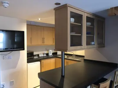 a kitchen with wooden cabinets and a tv on the wall at The Anchor Ely in Ely