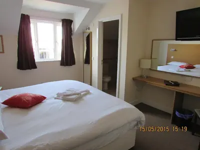 a bedroom with a bed with a red pillow and a mirror at The Anchor Ely in Ely