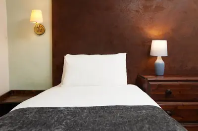 a bedroom with a white bed and a lamp on a dresser at Bull Hotel by Greene King Inns in Halstead