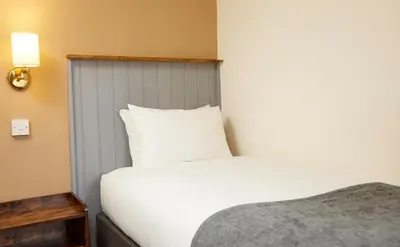 a bedroom with a white bed and a white pillow at Bull Hotel by Greene King Inns in Halstead