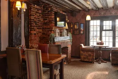 a dining room with a table and a brick wall at Bull Hotel by Greene King Inns in Halstead