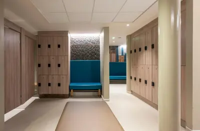 a locker room with wooden lockers and a blue bench at Park Farm Hotel in Norwich
