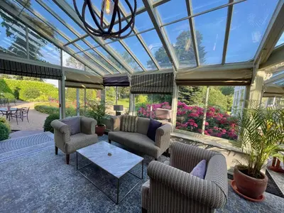 a conservatory with couches and chairs and a table at Park Farm Hotel in Norwich