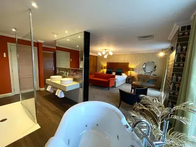 a bathroom with a bath tub and a living room at Park Farm Hotel in Norwich