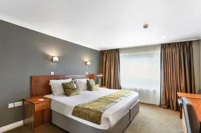 a hotel room with a large bed and a window at Stoke By Nayland Hotel, Golf & Spa in Leavenheath