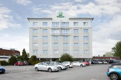 a large white building with cars parked in a parking lot at Holiday Inn Basildon by IHG in Basildon