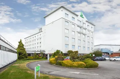 a white building with a parking lot in front of it at Holiday Inn Basildon by IHG in Basildon