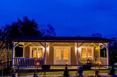 a small house with lights on the front of it at The Retreat Log Cabin in Sudbury
