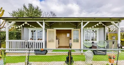 a small green house with a porch at The Retreat Log Cabin in Sudbury