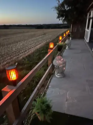 a row of lights on a fence next to a field at The Retreat Log Cabin in Sudbury