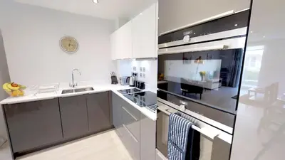a kitchen with white cabinets and a stainless steel refrigerator at Signet Apartments - Vesta in Cambridge