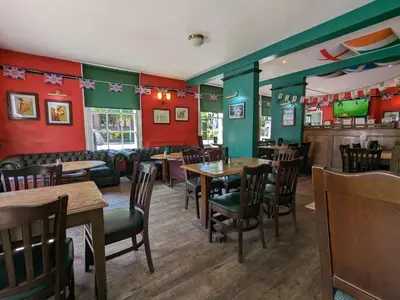 a restaurant with tables and chairs and red walls at The Earl Of Derby in Cambridge