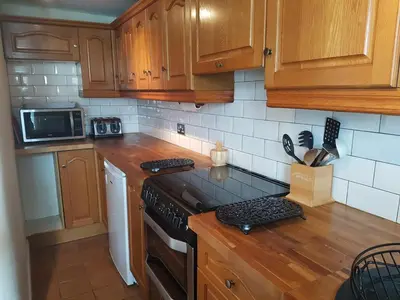 a kitchen with wooden cabinets and a stove top oven at Flint Cottage in Brandon