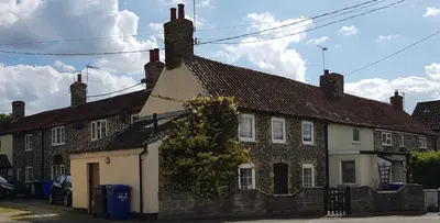 an old brick house with a white garage at Flint Cottage in Brandon