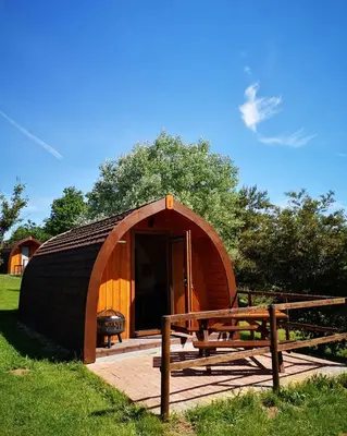 a small dome tent with a bench in a field at Cosy Camping Suffolk in Ipswich