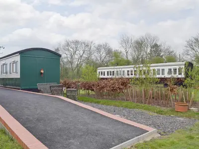 a train traveling down a road next to a building at Wilby Halt-Ukc712 in Wetheringsett